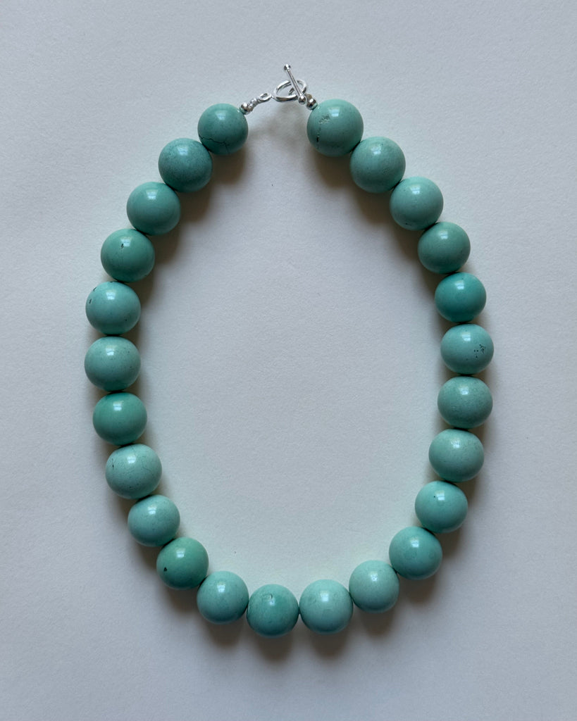 Turquoise beaded necklace on a light gray background